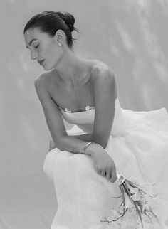 a black and white photo of a woman in a wedding dress sitting on a chair