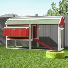 a small chicken coop with a slide in the grass