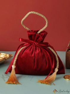 a red velvet bag sitting on top of a table next to a gold plated object