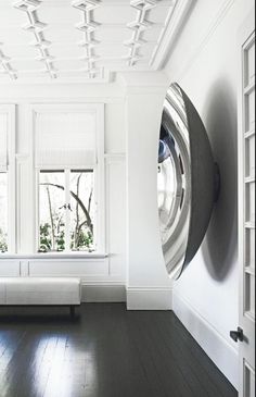 an empty room with white walls and wood flooring is seen in this image, there is a large circular mirror hanging on the wall