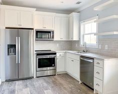 a kitchen with white cabinets and stainless steel appliances