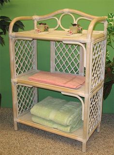 a bamboo shelf with towels on it in front of a green wall