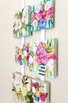 three colorful paintings hanging on the wall next to each other with flowers painted on them