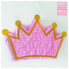 a pink and gold woven crown hanging from a string on a white background with the words momo origami pinatas mexicanas written below it