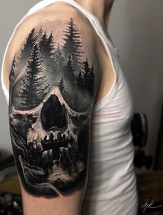 a man's arm with a skull and forest scene on the back of it