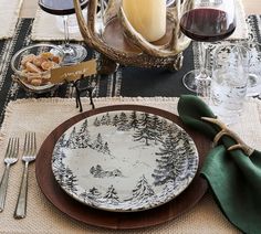 a place setting with plates, utensils and wine glasses