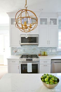 a bowl of fruit sitting on top of a kitchen counter next to an oven and microwave