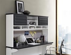 a desk with a laptop computer on top of it next to a chair in front of a window