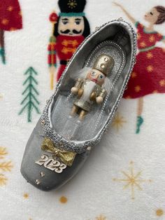 a pair of silver shoes with a nutcracker figure on the bottom and snowflakes in the background