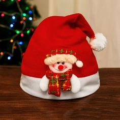 a red and white teddy bear wearing a santa hat on top of a wooden table