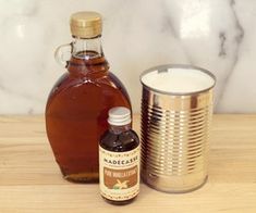 a bottle of syrup next to a tin can on a table