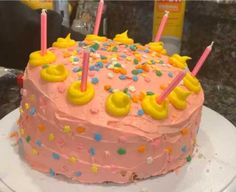 a pink birthday cake with lit candles on it