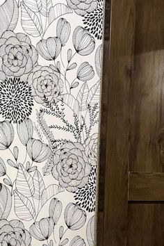 a black and white wallpaper with flowers on it in a room next to a wooden door