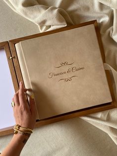 a person writing on a wedding guest book with a pen and ring binder next to it