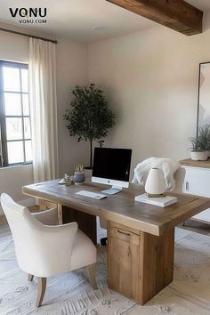 a desk with a computer on top of it in front of a window and white chairs