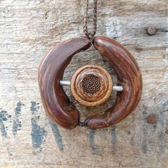 a wooden necklace with two pieces of wood hanging from it's center on a chain