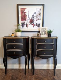 two black and gold painted nightstands with pictures on them