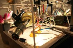 an assortment of items are displayed on a table with wires and other electrical equipment in the background