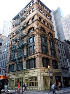 a tall building with lots of windows on the side of it's face and people walking around