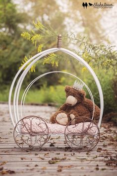 a teddy bear sitting in a miniature carriage