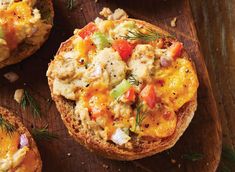 an open faced muffin topped with chicken and vegetables on a wooden cutting board next to other muffins