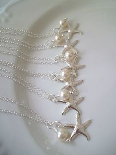 three starfish necklaces with pearls on a white plate in the middle of it