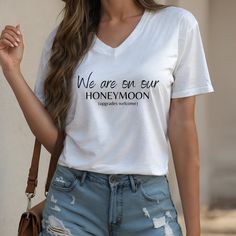 a woman wearing a white t - shirt with the words we are on our honeymoon printed on it