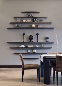 a dining room table with chairs and shelves on the wall in front of it,