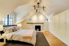 a bedroom with a bed, dressers and fireplace in the middle of the room