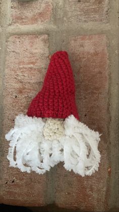 a red and white crocheted santa hat on top of a brick wall