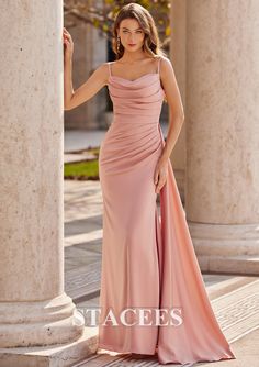 a woman in a long pink dress posing for the camera with columns and pillars behind her