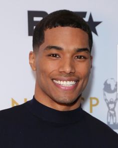 a young man smiling at the camera in front of a white wall with a star on it