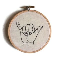 a cross stitch embroidered onto a wooden hoop with a peace sign on it's side