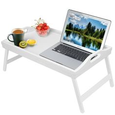 an open laptop computer sitting on top of a white table next to a cup of coffee