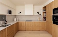 an empty kitchen with wooden cabinets and white counter tops, is pictured in this image