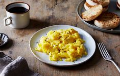 scrambled eggs on a white plate next to coffee