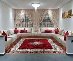 a living room filled with white couches and red rugs on top of a hard wood floor