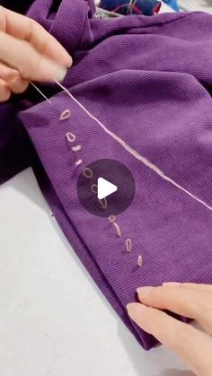 someone is stitching the letters on a purple shirt