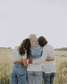 three women standing in a field hugging each other