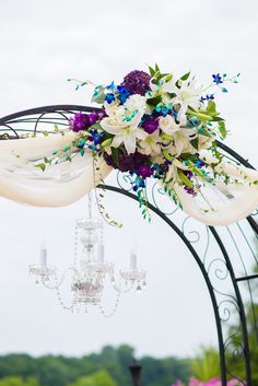 a wedding arch decorated with flowers and chandelier hanging from it's side