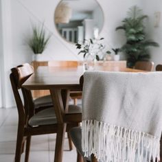 a dining room table and chairs with a white blanket draped over the wooden chair next to it