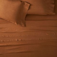 the bed is made with brown sheets and pillows