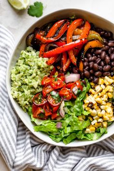 a white bowl filled with black beans, tomatoes, corn and guacamole