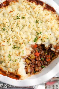 a casserole dish filled with meat and vegetables, topped with grated cheese