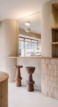 two wooden stools sitting in front of a counter next to a wall with shelves