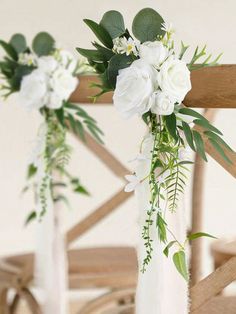 two vases filled with white flowers and greenery on top of a wooden chair