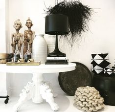 a white table topped with lots of vases and other decor items next to a black lamp