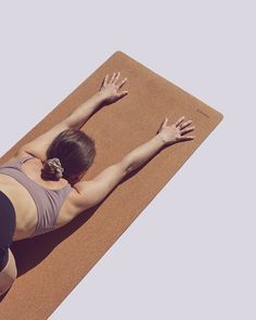 a woman is doing yoga on a mat with her hands in the air while stretching