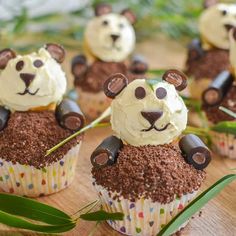 some cupcakes with chocolate frosting and teddy bears on top are sitting on a table