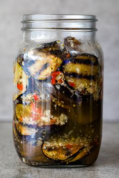 a jar filled with lots of food on top of a cement counter next to a wall